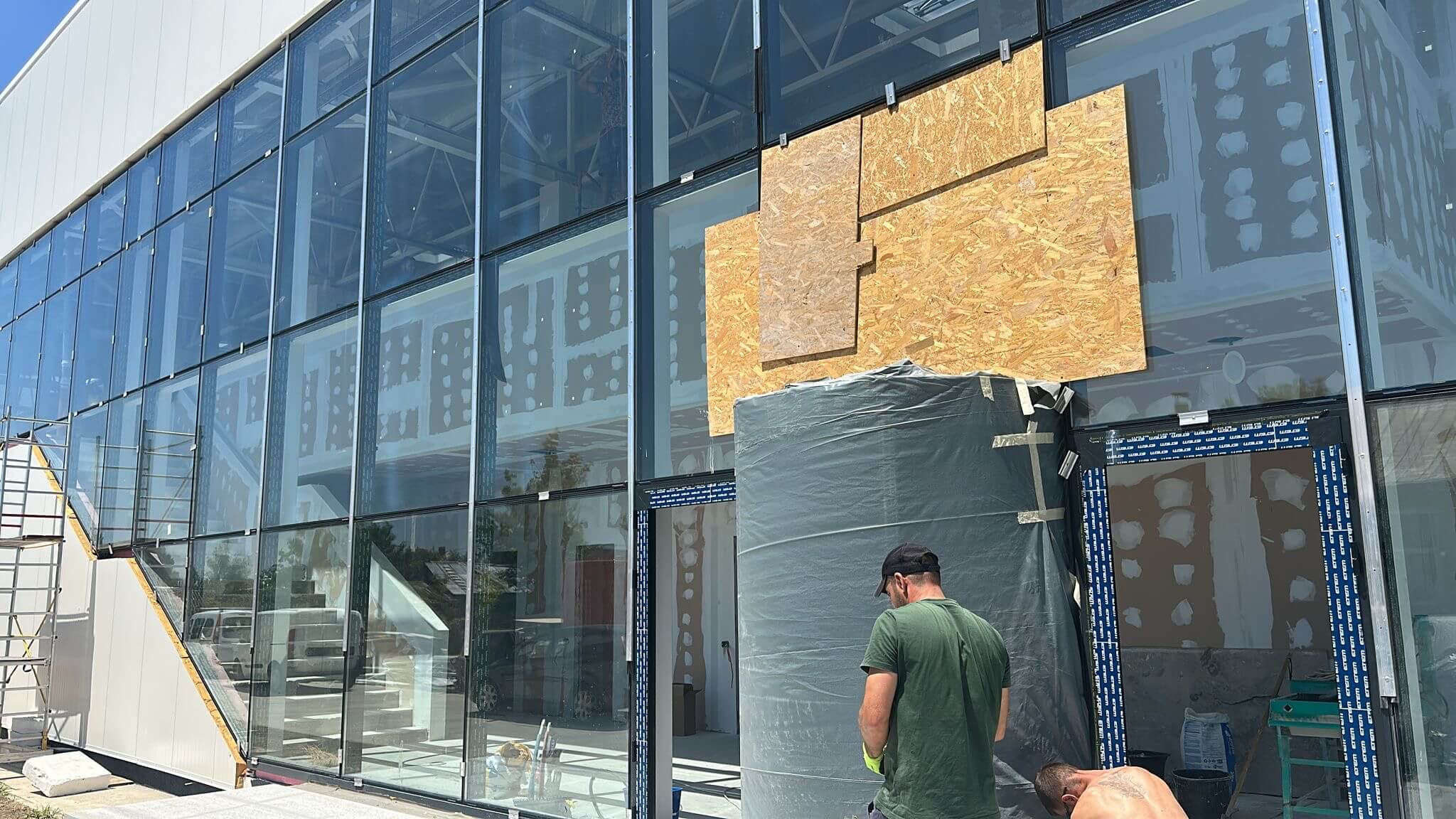 Montaj fațadă vitrată pe o clădire comercială, izolație termică aplicată deasupra vitrajului